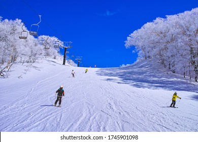 Skiers skiing on an intermediate course on a mid-winter slope - Shutterstock ID 1745901098