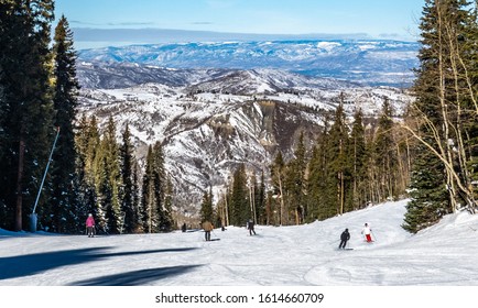 Skiers And Snowboarders Descend The Slopes Of The Aspen Snowmass Ski Resort, In The Rocky Mountains Of Colorado.  