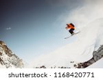 Skiier in the alps jumping down cliff in red jacket with blue sky and sunny weather