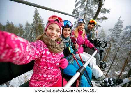Skiing, ski lift, ski resort - happy smiling family skiers on ski lift making selfie