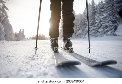 Skiing. Ski on First Tracks. Alpine skier going downhill skiing in morning on Fresh Tracks on groomed ski trail slope piste. Closeup of trail, skis and ski boots amongst snow covered trees. - Shutterstock ID 2082439054