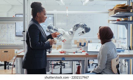 Skilful Black Specialist Explains Programming To Arabic Computer Science Major. Robot Limb Moving Under Her Control. People Designing Automated Robotic Systems For Modern Facilities Concept.