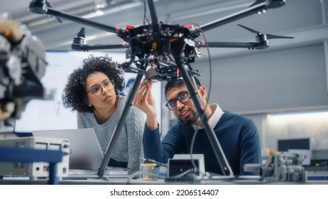 Skilful Male Engineer With Semiconductor Gives Advice To Black Female Computer Developer While She Is Writing Code For Drone Control. Technological And Innovative Startup Concept.