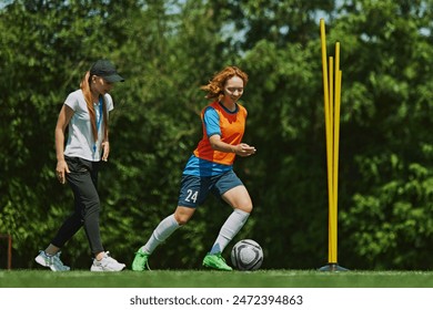 Skill Development on the Field. Female soccer player in bright sportswear training with her coach providing guidance to enhance her performance. Concept of sport, school, childhood, active lifestyle - Powered by Shutterstock