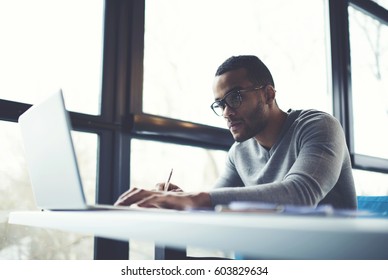 Skilled afro american male IT professional freelancer working on clients project updating software improving code of application working in coffee shop using laptop computer and wireless internet