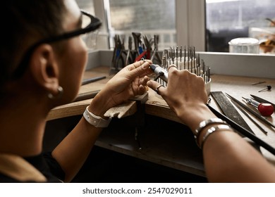 A skilled artisan crafts intricate jewelry in a bright, detail focused workspace. - Powered by Shutterstock