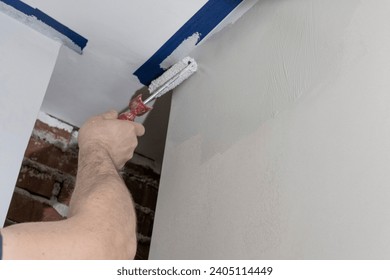A skilled artisan, using a roller, transforms a large room with precise and masterful painting.