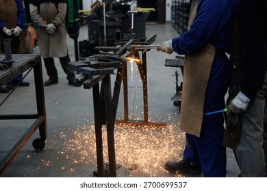 Skilled artisan using a welding torch to join metal pieces in a workshop, scattering sparks
