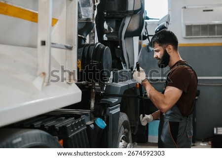 Skilled auto mechanic using tools to repair a truck in a professional garage, focusing on engine maintenance and problem-solving