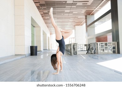 Skilled ballet dancer doing handstand while performing on urban scene - Powered by Shutterstock