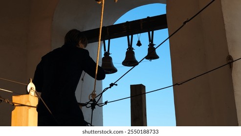 Skilled bell ringer pulls ropes, filling air with majestic bell sounds. Inspired by faith, he becomes part of sacred ritual, calling people to prayer and introspection. Bell Ringer in Service