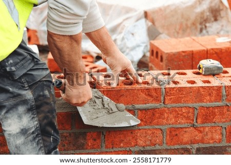 Skilled builder bricklayer laying bricks with precision at a construction site in the afternoon sun