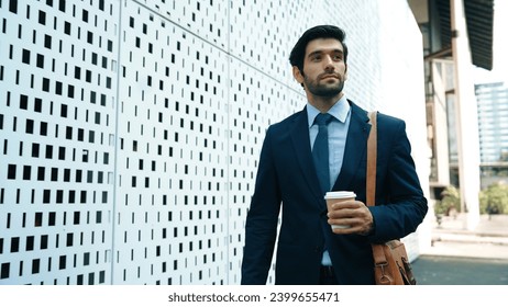 Skilled business man walking in suit outfit while holding coffee cup. Professional manager standing near architectural building. Going to working in morning, seeking for successful job. Exultant. - Powered by Shutterstock