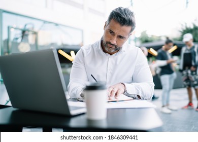 Skilled Businessman 40 Years Old Using Laptop Computer For Informative Research During Distance Working In Downtown, Middle Aged Male Employer Connecting To 4g Internet On Netbook While Planning