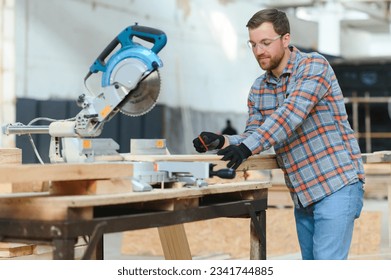 Skilled cabinet maker cutting wood board with electric circular saw at woodworking sawmill. Professional cabinet maker use circular saw at sawmill factory. Wooden furniture production - Powered by Shutterstock