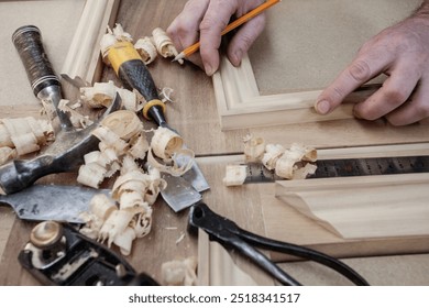 A skilled carpenter carefully measures a piece of timber, holding a pencil to mark precise cuts. Surrounded by tools, he's focused on his craft, showcasing hands-on woodworking in a workshop setting. - Powered by Shutterstock