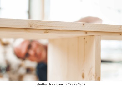 Skilled carpenter inspects wooden tabletop in cozy workshop, showcasing passion for woodworking - Powered by Shutterstock