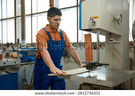 Skilled carpenter using bandsaw to shape curved panel while maintaining safety precautions and focus