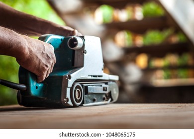 A skilled carpenter is using the power sander as a tool to polish his furniture instead of sandpaper.