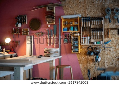 Skilled carpenter workshop equipped with wall mounted tool cabinet and sturdy workbench. Custom furniture production, wood crafting job, handmade woodworking, order fulfillment, professional tools
