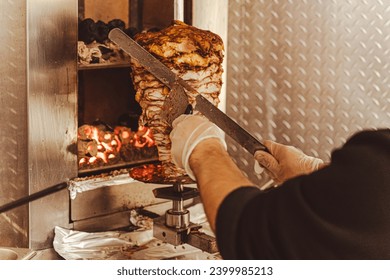 A skilled chef cuts pieces of meat from a rotating shish kebab skewer to prepare delicious shawarma, a popular and mouth-watering fast food delicacy.