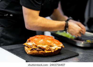 skilled chef meticulously crafts an open-faced sandwich, adorned with melted cheese and fresh tomato slices, showcasing culinary artistry - Powered by Shutterstock