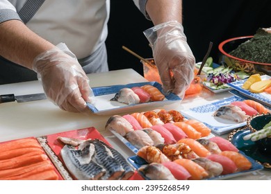 A skilled chef prepare a variety of sushi on a table. Mixing flavor, texture, and color, the chef creates culinary art. Each sushi is a precise masterpiece, showcasing their expertise and dedication. - Powered by Shutterstock