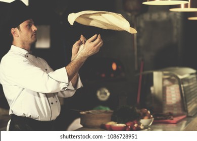 Skilled chef preparing dough for pizza rolling with hands and throwing up - Powered by Shutterstock