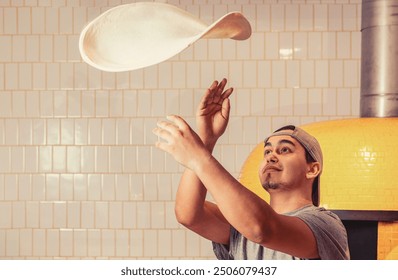 Skilled chef preparing dough for pizza rolling with hands and throwing up. Hands of a male chef with thin round pizza dough in the kitchen. - Powered by Shutterstock