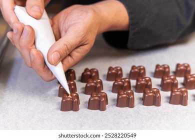 Skilled chocolatier filling caramel chocolate moulds with precision, showcasing artistry and care in gourmet confectionery making. Selective focus - Powered by Shutterstock