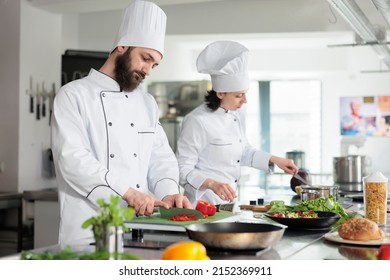 Skilled and confident head chef chopping organic and fresh red bell pepper while preparing garnish. Food industry worker cooking delicious gourmet dish for dinner service at restaurant. - Powered by Shutterstock