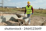 Skilled construction worker is transporting building materials on development site