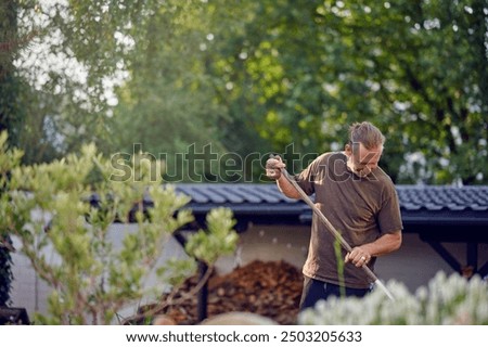 A skilled craftsman engaged in a hands-on outdoor task, carefully raking and maintaining a garden area