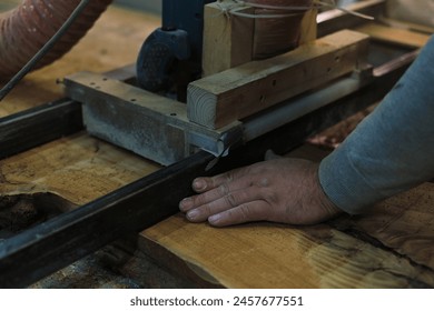 A skilled craftsman operates a bandsaw, precisely cutting a wood slab. Precision and safety are paramount in his work. - Powered by Shutterstock