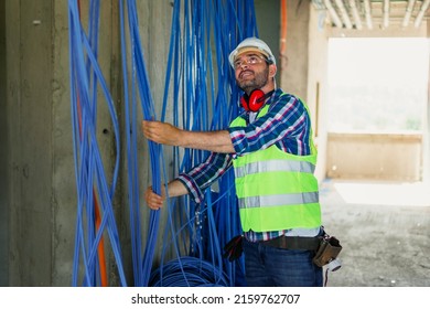 A skilled electrician in construction checking cables for building electric network.