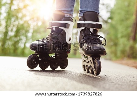 Skilled experienced inline skater making trick, spending free time with pleasure, trying new exercise, having training, rollerblading as hobby, being in middle of road. Rollerskating concept.