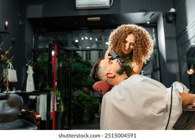 A skilled female barber styles a client's beard using a hairdryer in a contemporary setting, emphasizing luxury and personal care in male grooming - Powered by Shutterstock