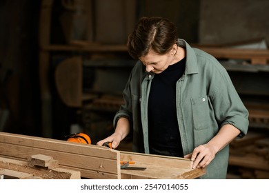 A skilled female carpenter carefully measures wood, demonstrating craftsmanship in her workshop environment. - Powered by Shutterstock