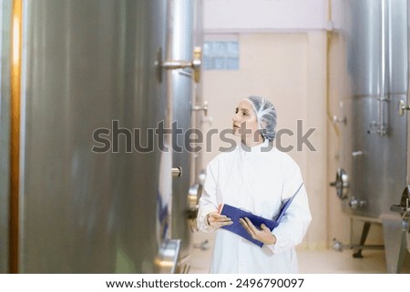 Skilled female engineer inspects complex machinery in beverage fermentation factory with precision and care. Her expertise ensures the seamless operation and high quality of the production process.