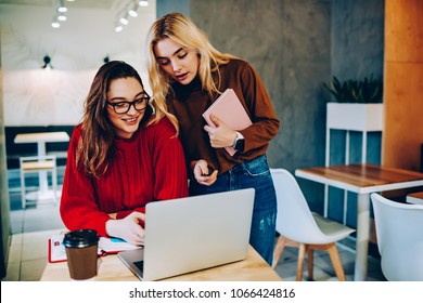 Skilled Female Students Making Research On Laptop Computer Doing Homework In College Campus,hipster Girls Communicating In University Library Watching Training Webinar Together On Netbook For Learning