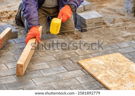 Skilled hands lay down bricks with care, ensuring each piece aligns perfectly on the sandy ground. This meticulous process highlights the artistry involved in masonry.