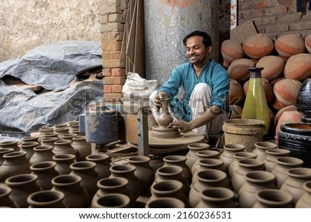 Skilled hands of a potter shaping the clay into pot on spinning wheel