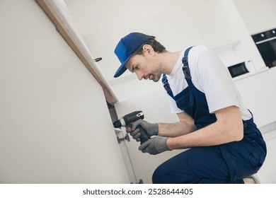 Skilled handyman using a drill for home repair in bright modern kitchen setting - Powered by Shutterstock