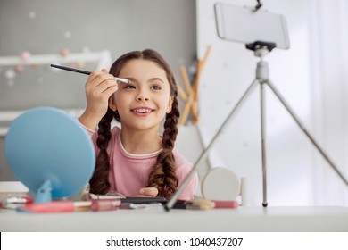 Skilled Kid. Pleasant Pre-teen Girl Applying Eye Shadows And Telling Her Audience The Correct Algorithm Of Actions While Filming The Tutorial With Her Phone On Tripod