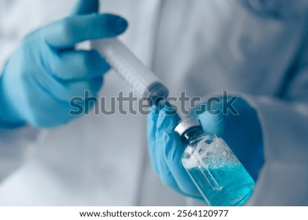 A skilled Laboratory Technician methodically preparing a precise dosage using a syringe and a vial containing a striking blue liquid, indicative of thorough biomedical research and testing