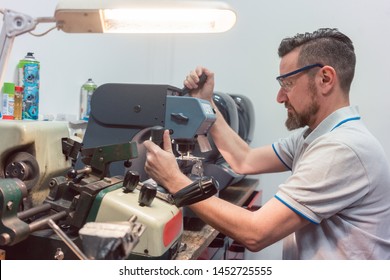 Skilled locksmith cutting key with his machine