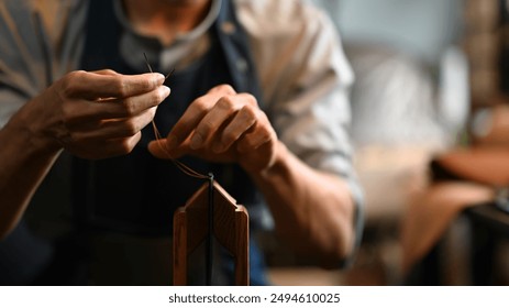 Skilled male artisan meticulously stitching a piece of leather. Craftsmanship and artisanal skills concept. - Powered by Shutterstock