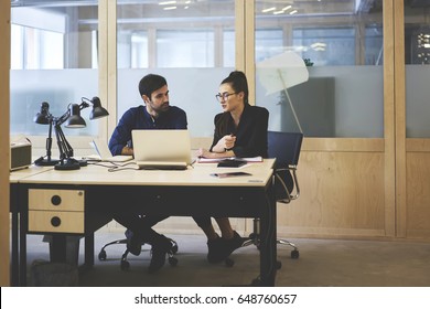 Skilled male and female It professionals talking to each other during working day in office testing application for digital devices on laptop computer consulting abut improvement of usability
