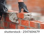 Skilled mason laying bricks with precision and attention to detail during construction in bright daylight