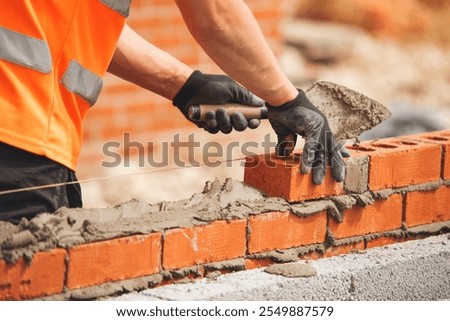 Skilled mason laying bricks with precision in a construction site during daylight hours